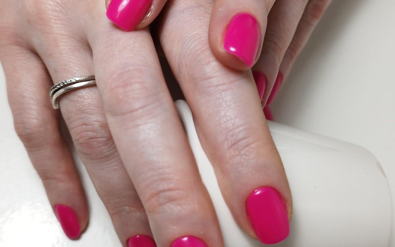 Glanzende fuchsia nagels en een zilveren ring