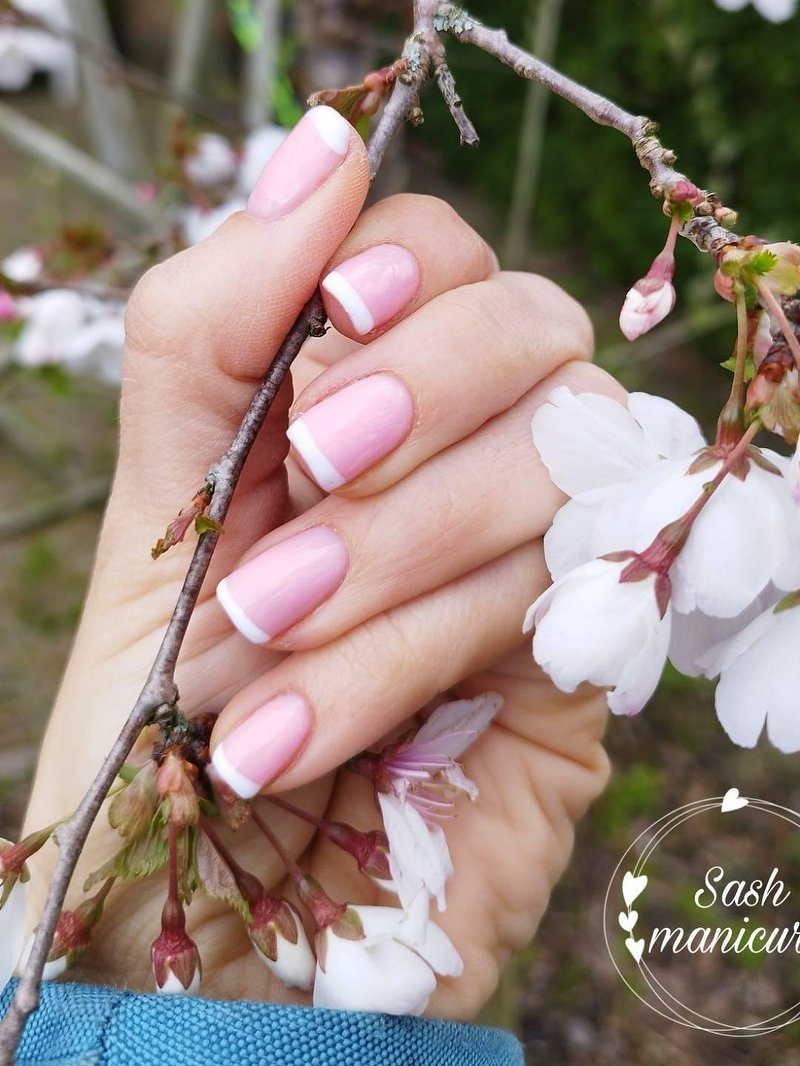 French nagels met een roze basis naast kersenbloesem