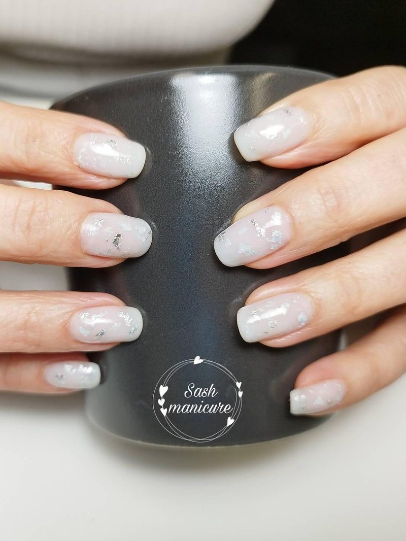 Lichtgrijze nagels met een marmerlook rond een mok